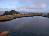 at the top of the highest mountain, water reflects the clouded valley